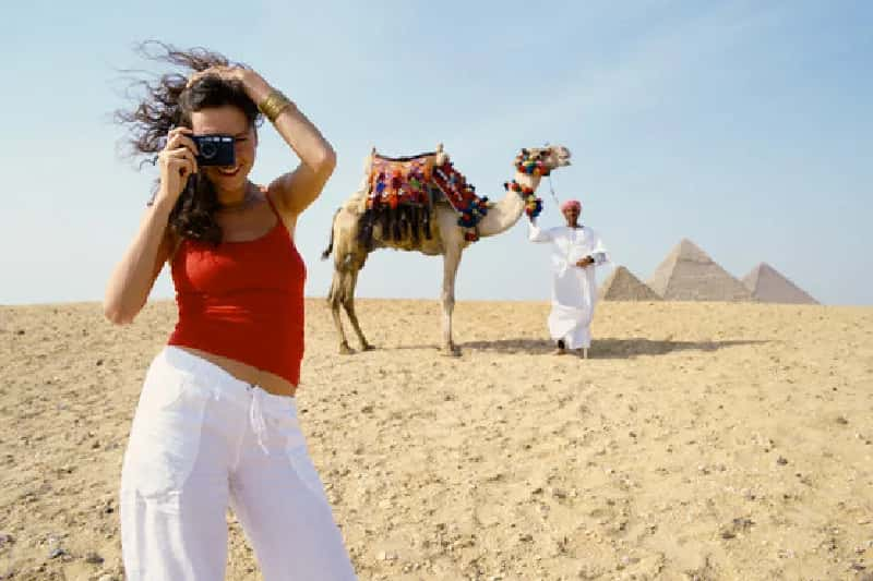 una turista scatta una foto alle piramidi , natale al cairo 